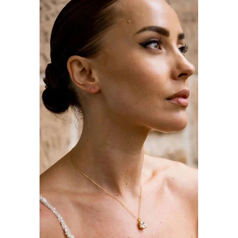 Gold-plated Elaine cushion-cut cubic zirconia pendant on a delicate chain worn by a woman for an elegant, sparkling look.